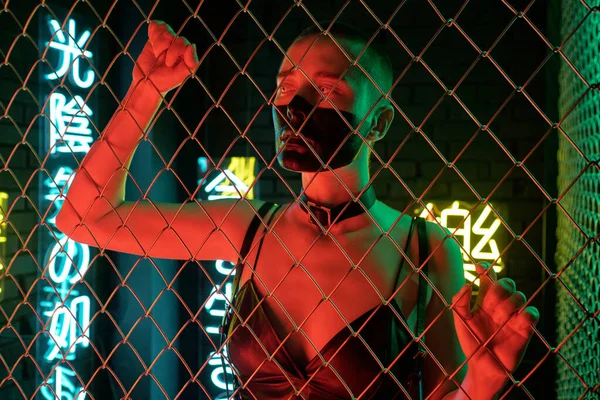 Cyberpunk-Mädchen in schwarzem Ledertanktop steht hinter Gittern — Stockfoto