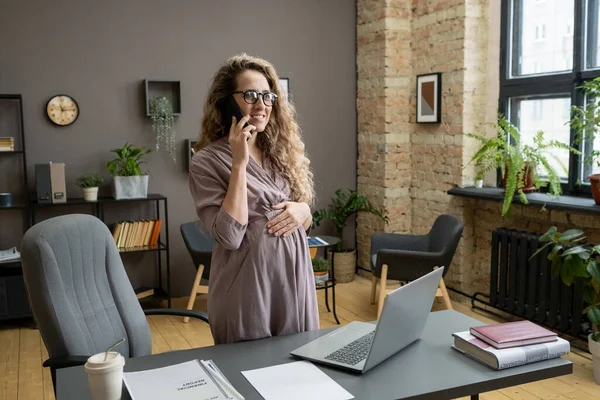 Mujer embarazada joven contemporánea hablando por teléfono móvil — Foto de Stock