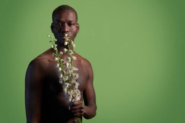 Yüzünde ve vücudunda beyaz çiçekler olan kaslı Afrikalı genç bir adam.