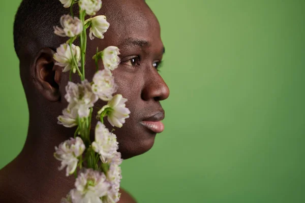 Vue latérale de la tête de l'homme noir et des fleurs blanches — Photo