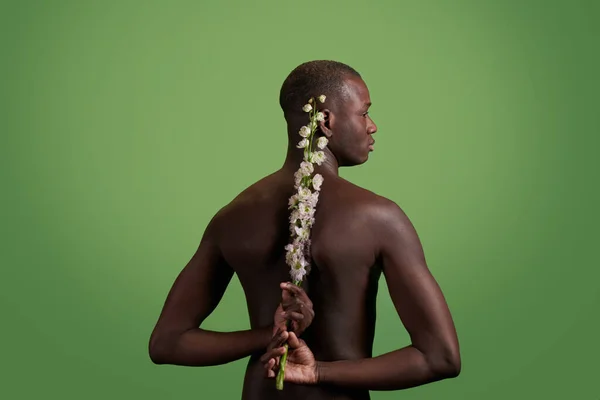 Espalda de joven musculoso hombre de etnia africana sosteniendo flores blancas — Foto de Stock