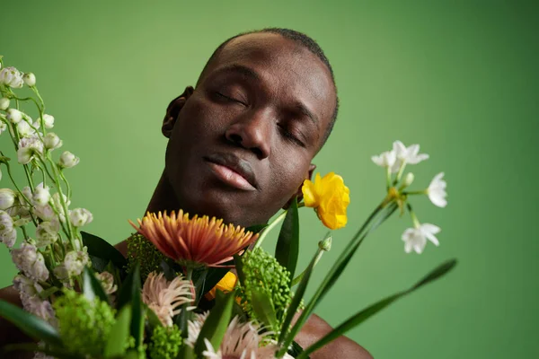 Jovem africano com olhos fechados apreciando o cheiro de flores — Fotografia de Stock