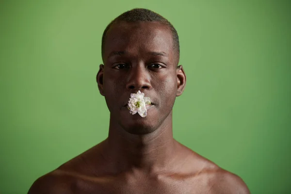 Młody Afrykanin z białym kwiatem w ustach patrzy na ciebie — Zdjęcie stockowe