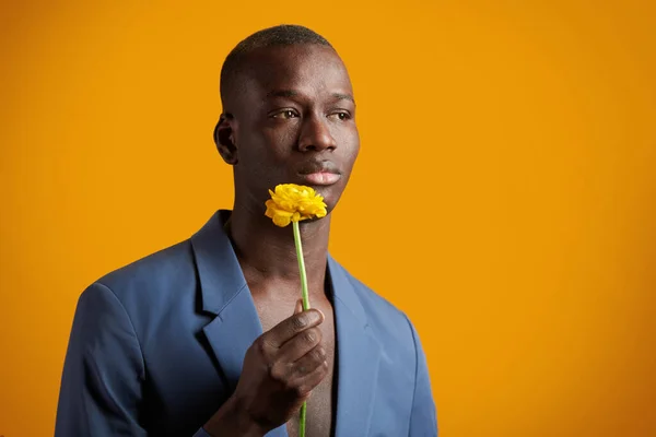 Junger romantischer Mann in blauer Jacke auf hemdslosem Körper mit gelber Blume — Stockfoto