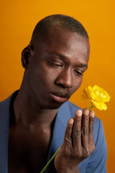 Przystojny młody człowiek patrząc na żółty kwiat w jego ręce — Zdjęcie stockowe