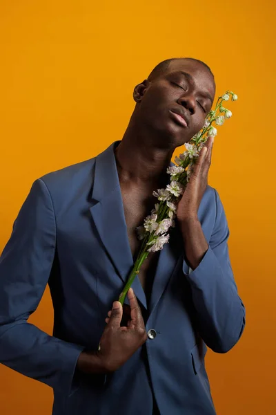 Afrikaner in blauer Jacke mit weißen Blumen vor dem Gesicht — Stockfoto