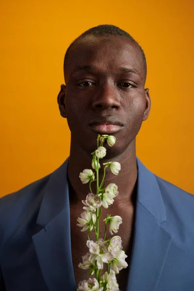 Poważny Afrykanin z białymi kwiatami patrząc przed kamerą — Zdjęcie stockowe