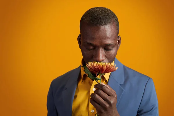Afroamerykanin młody człowiek pachnący kwiatem — Zdjęcie stockowe
