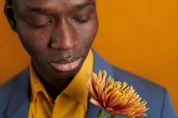 Twarz młodego Afrykanina patrzącego na żółty kwiat — Zdjęcie stockowe