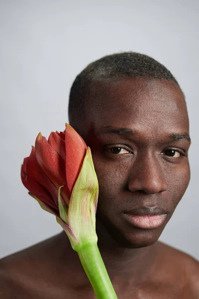 Chef för ung afrikansk man med knopp av stora röda blommor — Stockfoto