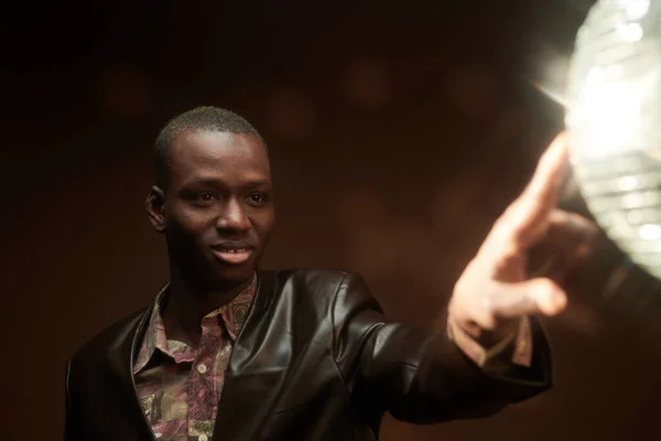Gelukkige jonge Afrikaanse man aanraken discoball in disco in de nachtclub — Stockfoto