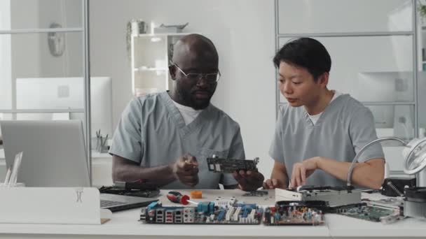Afroamerykański Inżynier Omawia Chip Komputerowy Azjatycką Koleżanką Podczas Wspólnej Pracy — Wideo stockowe