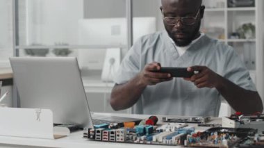 Afrika kökenli Amerikalı elektronik mühendisinin akıllı telefonuyla bilgisayar çipinin fotoğrafını çekerken görüntüyü yukarı kaldır.