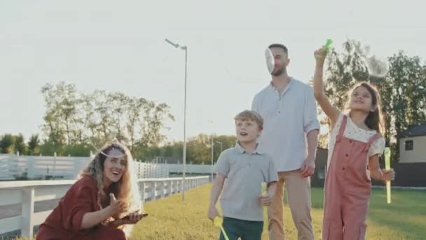 Beyaz Tenli Genç Anne Babaların Arka Işıklandırması Çimenlikte Sabun Köpüğü — Stok video