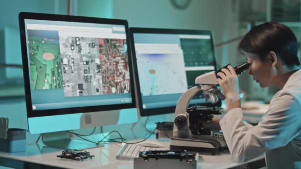 Foto Rastreamento Engenheira Técnica Feminina Jaleco Examinando Chip Sob Microscópio — Vídeo de Stock