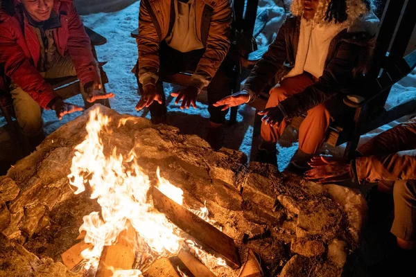 Les gens assis près du feu de camp à l'extérieur — Photo