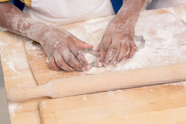 Mãos de criança pequena usando formas metálicas ao fazer cookies — Fotografia de Stock