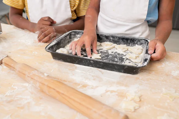 Handen van jongen snijden koekjes van opgerold deeg tijdens het koken gebak — Stockfoto