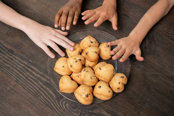 Hands of kids reaching to cookies — Stock Photo, Image