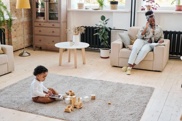 Jongen speelt met tablet terwijl moeder thuis werkt — Stockfoto