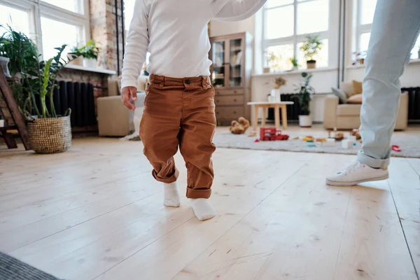 Peuter in witte sokken lopen met moeder door kamer — Stockfoto
