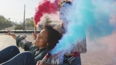 Alçak açılı, neşeli, beyaz, alışveriş arabalı, içinde dikkatsiz bir zenci kız olan bir adam. Arkadaşları, güneşli yaz gününde şehirde kırmızı ve mavi duman bombaları tutuyor ve gülümsüyor.