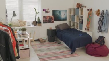 Masası, yatağı, pencere pervazında bitkileri, gündüz duvarlarında posterleri olan parlak ve temiz çocuk odası manzarası