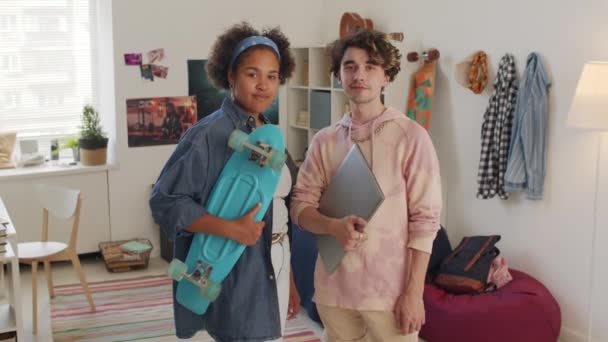 휴대용 컴퓨터를 곱슬머리 남자와 플라스틱 스케이트 보드를 침실에 카메라를 대학생의 — 비디오