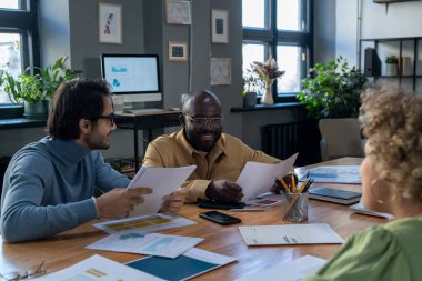 Kağıtları olan başarılı genç ekonomist bayan meslektaşına bakıyor.