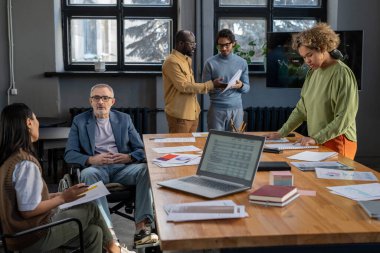 Birkaç meslektaşım çalışma noktalarını tartışıyor ve evrakları inceliyor.