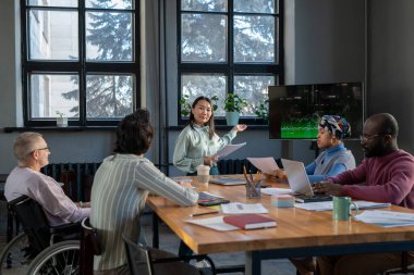 Genç Asyalı iş kadını interaktif ekranı grafikle işaret ediyor
