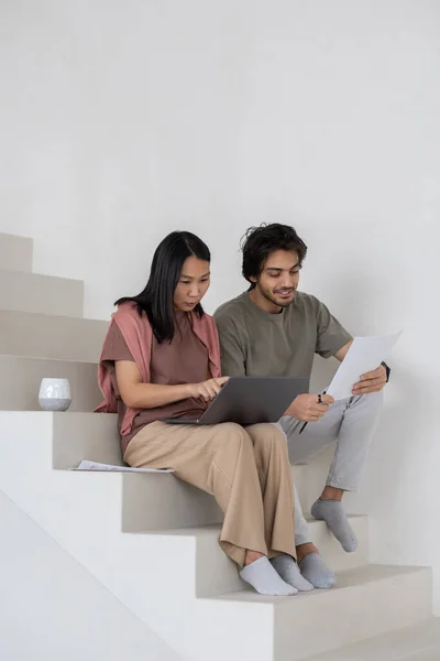 Glad ung affärsman med dokument sitter av kvinnlig kollega med bärbar dator — Stockfoto