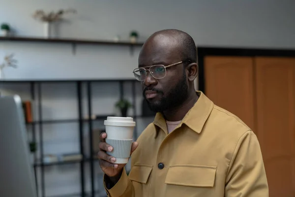 Jonge serieuze office manager met drank op zoek naar computerscherm — Stockfoto