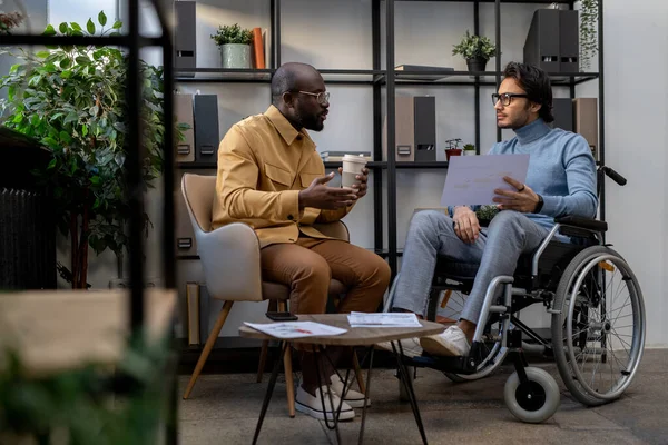 Afrikaans-Amerikaanse zakenman in gesprek met zijn blanke collega in rolstoel — Stockfoto
