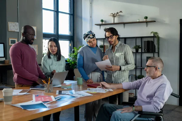 Group of intercultural colleagues discussing online financial data and papers — Stock Photo, Image