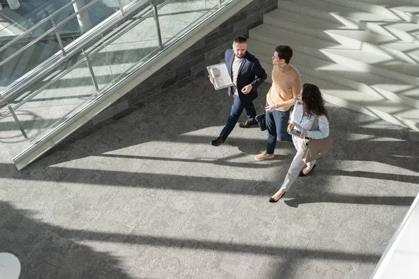 Вид зверху на трьох молодих співробітників, що рухаються вниз в коридор офісного центру — стокове фото