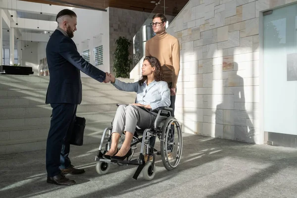 Mujer con discapacidad sentada en silla de ruedas con el apretón de manos con su pareja — Foto de Stock
