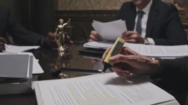 Ofis masasındaki belgeleri incelerken kadın avukatın metni fosforlu kalemle işaretlemesini kapat