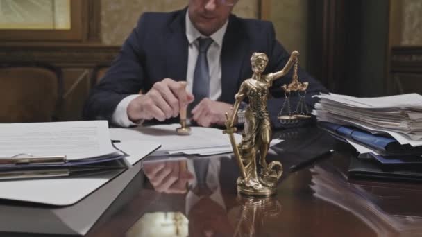 Erkek Avukatın Ofis Masasında Üzerinde Themis Heykeli Olan Belgeleri Damgaladığı — Stok video