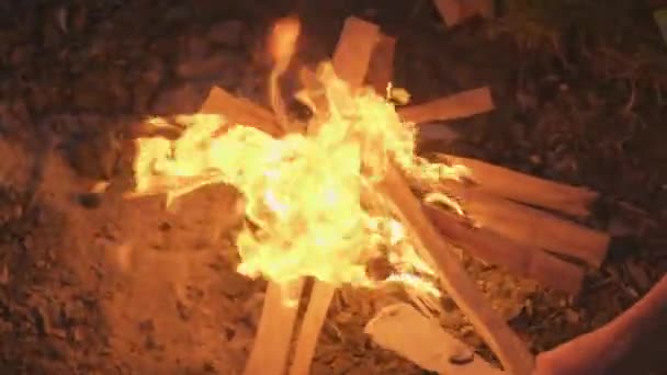在湖滨的营地里 一个无法辨认的人在营房里燃起篝火 在营房里加柴火 — 图库视频影像