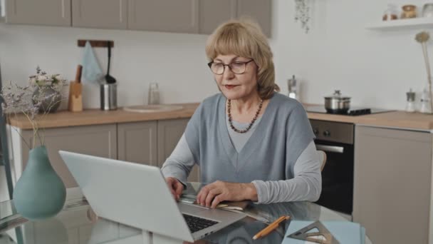 从家里上网学习时 坐在厨房餐桌旁 拿着笔记本电脑和复印机 摆好姿势拍照的白人妇女的画像 — 图库视频影像