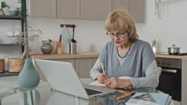 Senior Blanke Vrouw Zitten Aan Keukentafel Notities Maken Praten Video — Stockvideo