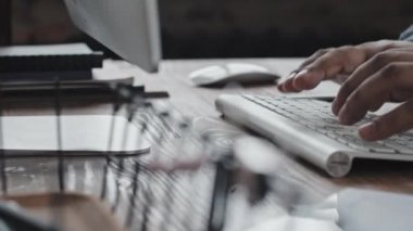 Masadaki kablosuz bilgisayar klavyesinde yazan tanınmayan iş adamının ellerinin yakın takibi.