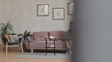 Afro-Amerikalı bir kadının oturma odasındaki koltukta oturup online video görüşmesinde sohbet etmesi.