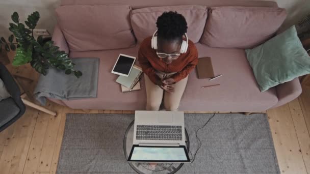 非洲裔美国女学生坐在沙发上 坐在笔记本电脑上通过视频通话 同时在家里上在线课程的自上而下的照片 — 图库视频影像