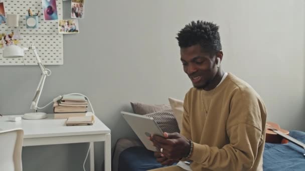Afroamerikaner Mit Drahtlosen Kopfhörern Sitzt Schlafzimmer Und Chattet Bei Online — Stockvideo
