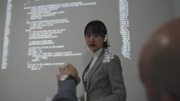 成功した若いアジアの実業家の低角度は 正式なスーツを着て 白い壁のそばに立ってコンピュータコードの投影 プレゼンテーション クロップド同僚の質問をする — ストック動画
