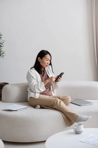 Young Asian Female Freelancer Smartphone Texting Searching Net While Sitting — Stock Photo, Image