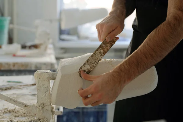 Mãos de jovem trabalhador da fábrica removendo gesso excessivo da superfície do molde — Fotografia de Stock