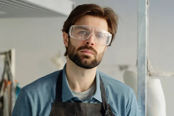 Young serious workman in apron and protective eyewear — Stock Photo, Image